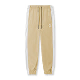 Flatlay of khaki ripstop oversized track pant with white side stripe, front view