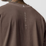 Tech Essential Relaxed Tee in Faded Dark Earth worn by model, back view showing vertical text detail