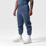 Tech Essential Sweats in faded navy joggers, worn by model with white sneakers, side view