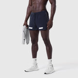 Aerotex 3" Distance Short in navy, worn by model holding grey jacket