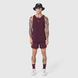 Aerotex Perforated Run Tank in merlot with matching shorts, modeled with white sneakers and black bucket hat