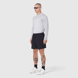 Revolutional Training Short in black, modeled with long-sleeve top and white sneakers, side view