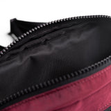 Flatlay 1231 Ripstop Crossbody Bag in Crimson, detail closeup of zipper