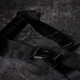 flatlay WN'19 Camera Strap in black with buckle closures on dark textured surface