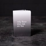flatlay SM'22 OTWR Notebook in black and white gradient, front view on dark surface