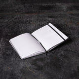 Flatlay of SM'22 OTWR Notebook in white and black, open pages view on dark textured surface
