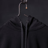FA'20 Contrast Thread Hoodie in black, hung on metal hook showing drawstring detail