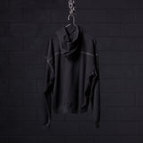 Black contrast thread hoodie displayed on hanger against dark brick wall background