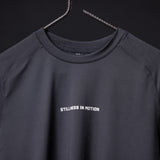 SM'22 Established Tee in charcoal gray on hanger, front view showing 'Stillness in Motion' text