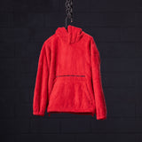 Red sherpa recovery hoodie hanging on chain against dark brick background