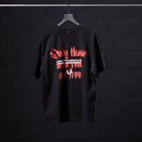 Black Tech Essential Relaxed Tee with red 'Risk Protocol' graphic design, displayed on hanger
