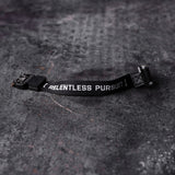 flatlay of black Cobra Buckle Bracelet with 'Relentless Pursuit' text on concrete surface