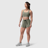 Tetra-Lite Linerless Short in sage, modeled with matching sports bra and white sneakers