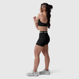 Black LYCRA® Hybrid Sports Bra worn by model in side profile, paired with black shorts