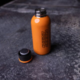 flatlay of ASRV Training Division water bottle in orange with black cap, shot from above on concrete surface