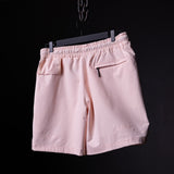 flatlay of pink Coastal Training Short on black hanger against dark background, back view