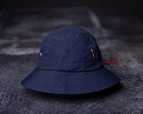 flatlay WN'22 Cinch Bucket Hat in navy blue, front view on dark concrete surface