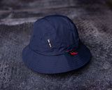 flatlay of navy blue Cinch Bucket Hat on textured gray surface