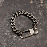 flatlay Carabiner Curb Bracelet in silver, top view on textured gray surface