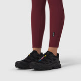 Crimson ribbed leggings worn with black athletic shoes, lower body view