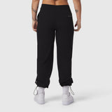 Black ripstop relaxed track pant worn by model, back view with cuffed ankles and white sneakers