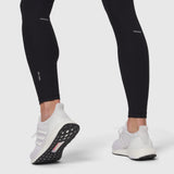 Black Lycra ribbed running tight worn with white sneakers, lower body view