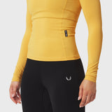 LYCRA® ADAPTIV Baselayer Longsleeve in amber yellow, worn with black leggings, side view