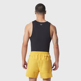 Black LYCRA® ADAPTIV baselayer tank on model, rear view, paired with yellow shorts