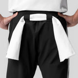 Black cuffed training jogger worn by model, front waistband detail with white towel
