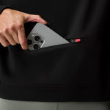 Black French-Terry Cropped Hoodie being held by model, showing pocket detail with earbuds