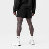 Black waffle knit sweat shorts worn with white socks and sneakers, back view