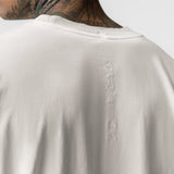 Tech Essential Relaxed Tee in Faded Stone worn by model, back view showing vertical embroidered branding