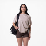 Tech Essential Relaxed Tee in faded chai worn with brown shorts and black backpack, front view