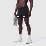 Aerotex 3" Distance Short in black, worn by model holding gray jacket