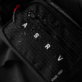0703 Cordura Tech Crossbody Pack in black grid, carried with red zipper pull visible