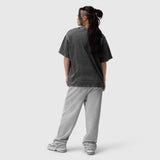 Distressed relaxed tee in black worn with grey joggers, back view