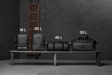 Flatlay of water resistant modular backpacks in black, various sizes displayed on bench