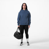 Tech Essential Distressed Hoodie in faded navy worn with black leggings, model holding black duffle bag