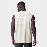 Tech Essential Relaxed Cutoff tank in stone, worn by model, back view showing 'only those who risk are free' text