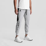 Slate grey cuffed training jogger with black side panels and LVNO branding, worn with white sneakers