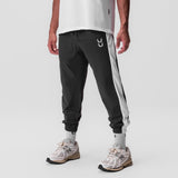 Ripstop Oversized Track Pant in black with grey side stripe, worn with white socks and sneakers