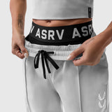 Model wearing grey ripstop relaxed track pants with black ASRV waistband, front view