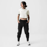 ASRV x Tonal Women's AeroSilver® Cropped Training Tee in ivory cream, worn with black cargo joggers