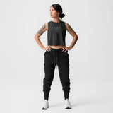 Black cropped training tank with TONAL branding, worn with black joggers and white sneakers
