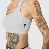 W096 LYCRA® ADAPTIV Racerback Sports Bra in Slate Grey, worn by model with tattoos, side view