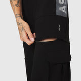 W100 2-in-1 Convertible Pant in black, worn by model showing zippered cargo pocket detail